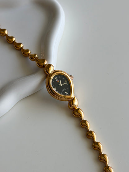 Vintage gold-tone watch with a striking black dial