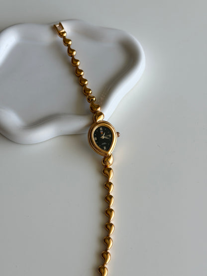 Vintage gold-tone watch with a striking black dial