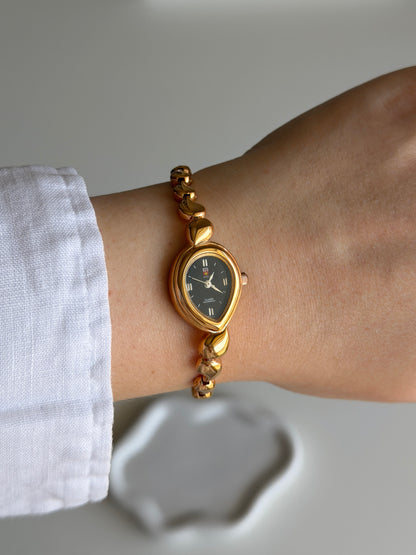 Vintage gold-tone watch with a striking black dial
